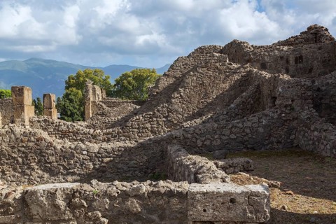 Old stone wall structures of varying heights and remnants of residential buildings at the ancient