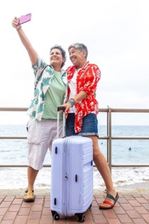 Two mature lesbian women take a selfie together by the seaside, celebrating their summer holiday