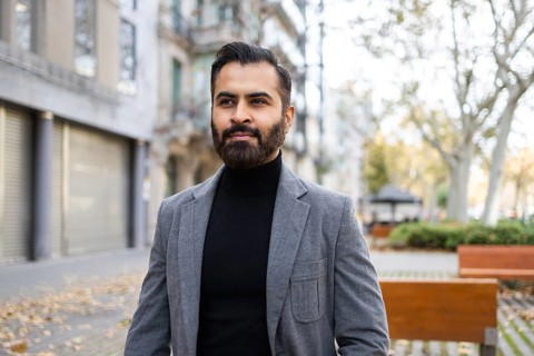 Indian businessman dressed in winter attire, sporting a stylish beard, standing confidently on a