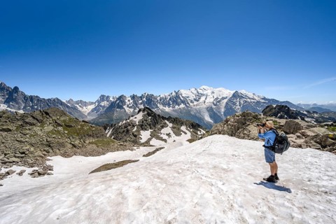 Mountaineer taking a photo, crossing a snowfield, mountain landscape with mountain peak Mont Blanc,