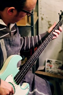 A skilled luthier works meticulously on a bass guitar in a workshop, showcasing the art of