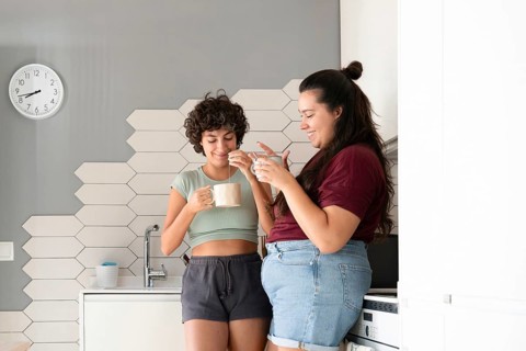A loving lesbian couple enjoys a morning coffee together in their modern kitchen. They share smiles