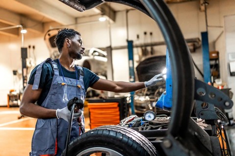 Young mechanic working on car maintenance, inspecting wheel and chassis in a professional auto