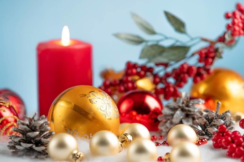 Glowing candle with golden baubles, red berries and pine cones, winter festive decoration