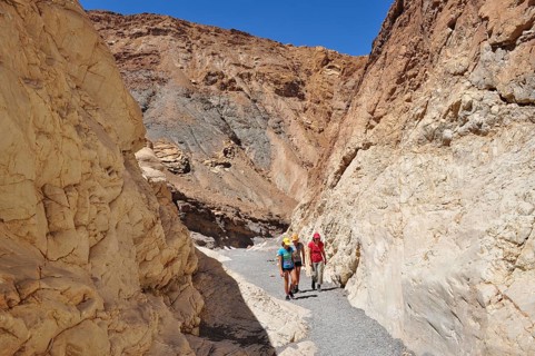 Three hikers in a narrow, sun-drenched gorge, Death Valley National Park, Mojave Desert,