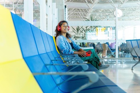 A traveler enjoys a moment of relaxation in a bright airport terminal, sitting on a colorful bench
