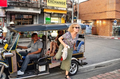A Thai tuk tuk driver smiles as he transports tourists through the bustling streets of Chiang Rai,