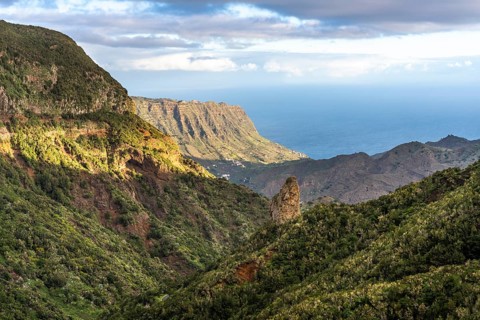 View of the valley of Hermigua and the sea. Mountains, hillsides with forest, palm trees, rocks.