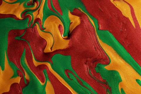 A textured background showcasing swirling patterns of metallic red, green, and yellow paints, ideal