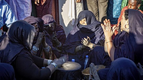 Women concentrate on drumming and prayer, in black and purple clothing, Traditional woman make