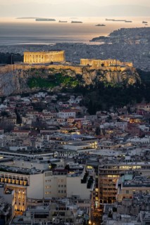 View over the sea of houses of Athens, illuminated Parthenon temple on the Acropolis, from Mount