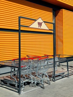 A collection of shopping carts stacked neatly in a cart corral outside a modern industrial