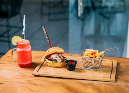 Big beef burger with fries and refreshing drink served on wooden table
