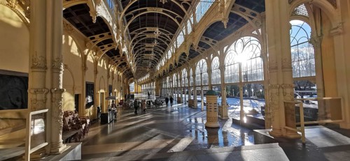 Large, sun-drenched interior of a historic hall with arched windows and columns, wellness,