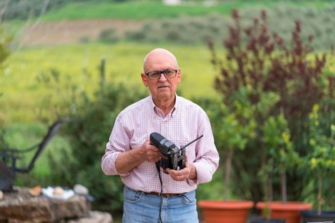 Senior man confidently holding a jigsaw with a serene natural backdrop, looking at camera, engaging