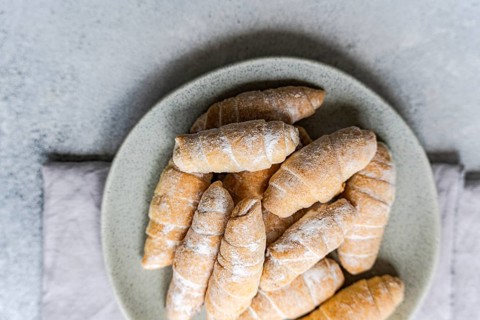 From above, a plate filled with delicious homemade pastries sprinkled with fine flour. The pastries