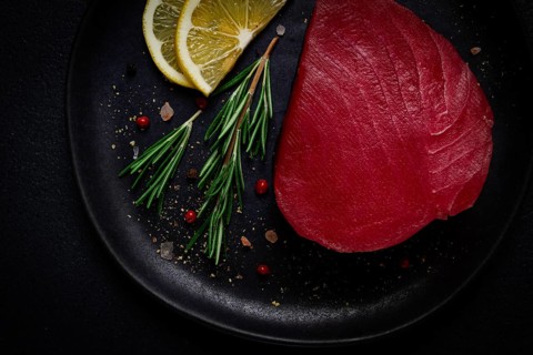 Fresh red tuna fillet, for steak, raw, top view, on a black plate, no people