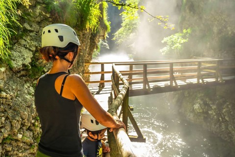 Mother and child wearing helmets, enjoying breathtaking view of wooden bridge over radovna river in