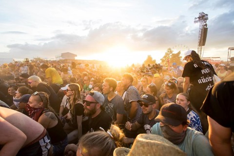 Festival visitors in front of the setting sun during the performance of the band Feine Sahne