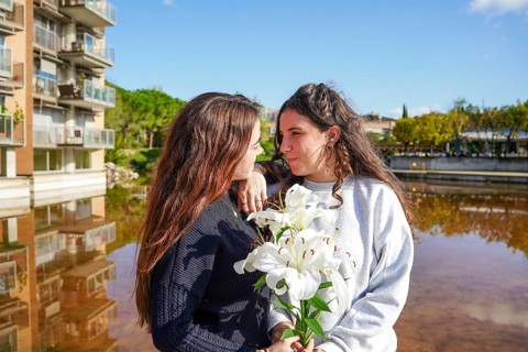 A romantic young women couple, members of the LGBTQ+ community, share a tender moment outdoors.