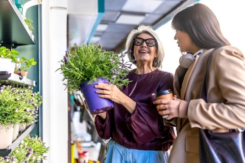 Two diverse women enjoying a joyful shopping experience at an outdoor flower shop, discussing a