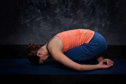 Beautiful sporty fit yogini woman practices yoga asana balasana (child's pose), resting pose or