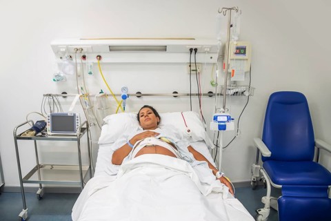 A new mother in a hospital bed, ready to give birth. Surrounded by medical equipment, she rests