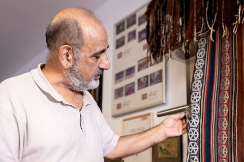 An Iranian master examines and restores rare carpets in his well-equipped workshop located in