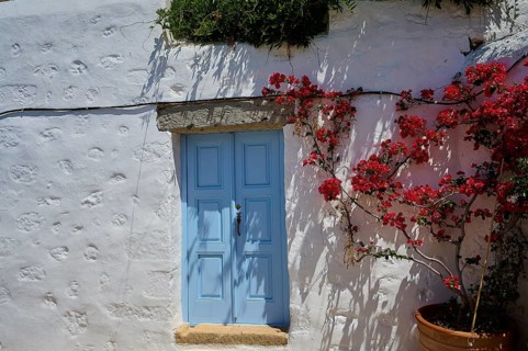 White house with blue door, red flower tendril, sunny day, Mediterranean landscape, Chora, main