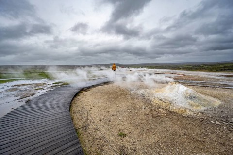 Tourist on a wooden path, steaming fumarole, Hveravellir geothermal area, Icelandic highlands,