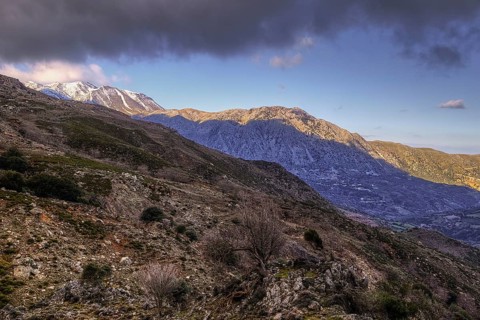 Stony mountain landscape with snow-covered peaks under a slightly cloudy sky, Lefka Ori, White