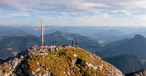Two hikers at the summit, aerial view, evening mood in the mountains, summit cross of the