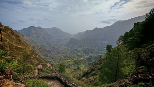 Panoramic, spectacular view over a valley with a winding path, hiking trail and mountains in the