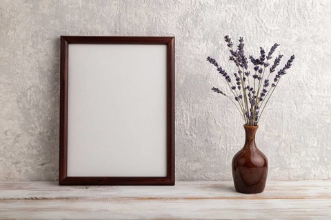 Brown wooden frame mockup with lavender in ceramic vase on gray concrete background. Blank,