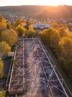 Car park in evening sunlight surrounded by trees in front of a mountainous landscape, Nagold,