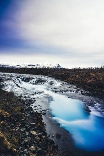 The stunning Bruarfoss waterfall, known for its crystal-clear turquoise waters, flowing over dark