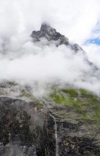Cloud-covered mystical gorge with waterfall and mountain peak, hiking to Berghaus Bäregg, Bernese