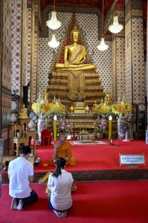 Praying in front of a Buddha statue in Wat Arun, Temple of Dawn, Bangkok, Thailand