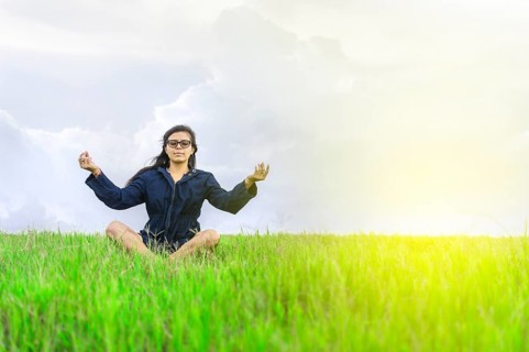 Woman meditating in the field. Relaxed woman doing yoga in the field