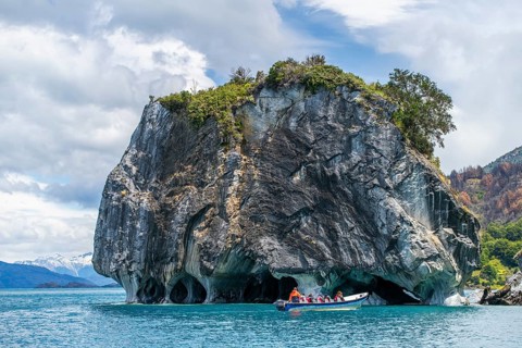 Motorboat with tourists at the rock formation of the marble cathedral, Cuevas de Marmol, marble
