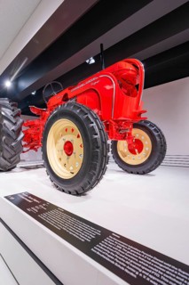 Close-up of a red vintage tractor with big tires in an exhibition, Porsche Museum, Stuttgart,