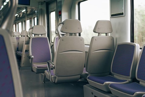 The photo depicts an empty train interior featuring modern gray seats with purple fabric accents.