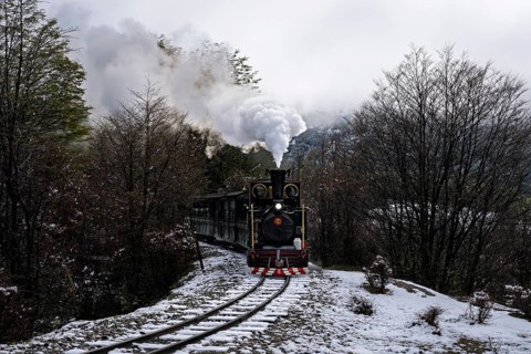 Tren del Fin del Mundo steam locomotive with passenger car on narrow-gauge track, snowy landscape
