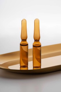 Close-up view of two amber-colored cosmetic ampoules containing anti-aging serum, displayed