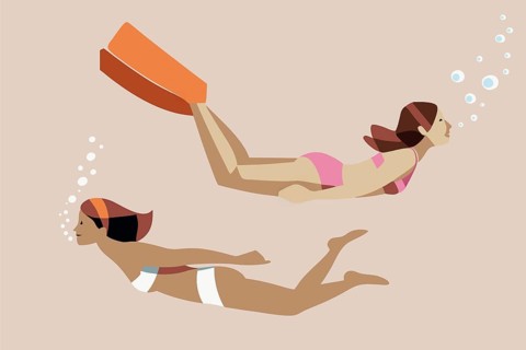 Two women with diverse appearances swim underwater while wearing fins. One woman is in a pink