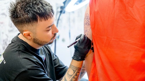 A tattoo artist skillfully inks a detailed dog tattoo on a person's arm, showcasing his