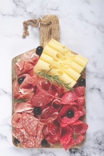 Assorted meat, appetizer, prosciutto, salami and ham, with maasdam cheese and olives, on a wooden