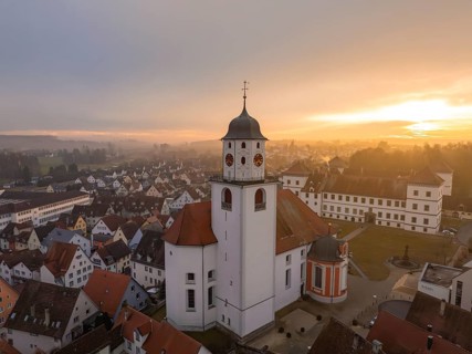 Church in a village at sunset with red roofs and cloudy sky, Meßkirch, district of Sigmaringen,