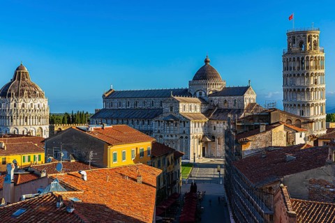 Above the roofs of Pisa in the morning light, behind the Baptistery, the Cathedral of Santa Maria