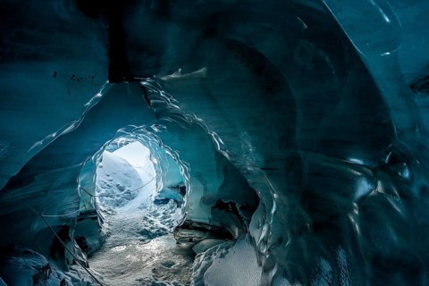 A mesmerizing view from within an ice cave at Katla Glacier, Iceland. The smooth, blue walls of the
